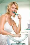 Woman in bathroom brushing teeth smiling