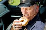 Police officer biting into a delicious glazed donut.