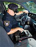 Police officer using the control panel in his squad car to turn on the lights and siren.