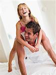 Man and young girl in bed playing and smiling