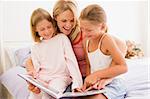 Frau und zwei junge Mädchen im Schlafzimmer Lesebuch und Lächeln