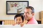 Man and young boy in living room with flat screen television smi