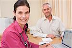 Doctor with laptop and man in doctor's office smiling