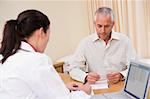 Doctor with laptop and man in doctor's office