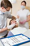 Dentist and assistant in exam room with man in chair