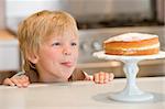 Boy staring longingly at cake at home licking lips