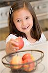 Girl taking apple from fruit basket at home