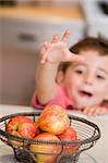 Boy reaching for apple from fruit basket