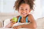 Young girl eating apple in living room smiling