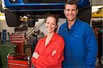 Two mechanics standing in garage smiling