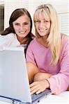 Two women on patio using laptop smiling