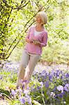 Woman walking outdoors holding flower smiling