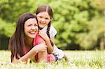 Mother and daughter lying outdoors smiling