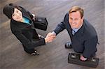 Two businesspeople indoors shaking hands smiling