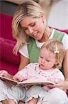 Mother in living room reading book with baby smiling