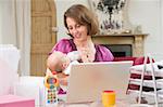 Mother and baby in home office with laptop