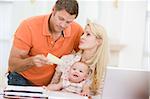 Couple and baby in dining room with laptop and paperwork