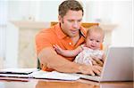 Father and baby in dining room with laptop