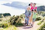Family walking on cliffside path pointing and smiling