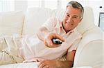 Man in living room using remote control smiling