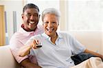 Couple in living room using remote control smiling