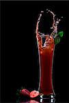 View of strawberry juice splashing out of glass on black back