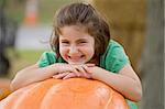 Little Girl Smiling on Top of a Big Pumpkin