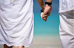 close up photo of romantic couple holding hands at the beach