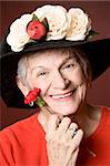 Senior woman in a red shirt and hat with flowers