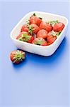 White plate with strawberry, on blue background