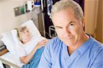 Doctor Standing In Patients Room,Looking Serious