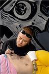 A tattoo artist applying his craft onto the abdomen of a female.