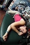 A tattoo artist applying his craft onto the lower leg of a pain-inflicted female.