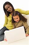 A beautiful young African American mother and her mixed race young daughter using a laptop at home on a settee