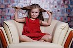 Little cute girl in red dress puling her hair.