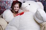 Little cute girl in red dress with big smile holding Teddy bear.