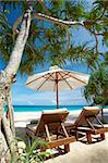 view of two chairs and white umbrella on the beach.