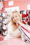 The smiling blonde in shop of bras costs at a counter