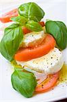 Slices of tomato and mozzarella with pepper, olive oil and mint