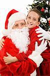 Cute little boy giving Santa Claus a big hug on Christmas morning.