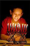 Little boy gazing on a lighted menorah, illuminated only by its light.  Shallow depth of field with focus on boy's eyes.