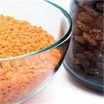 abstract image of glass jars filled with red lentils and haricot against white background