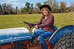 Beautiful mature woman driving a tractor on her farm.