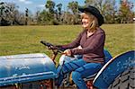 Beautiful mature woman driving a tractor on the farm.