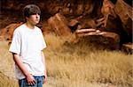 teen boy in Wyoming wilderness area, large red-brown boulders in background, copyspace