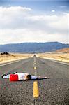 out of gas - teen male laying dead in the middle of a remote rural highway still clinging to red gas can