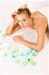 Beautiful young woman relaxing in spa surrounded by aromatherapy items