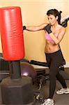 Attractive young woman training kickboxing using red punching bag