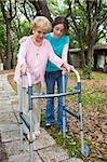 Teen girl helps her aging grandmother to walk using a walker.