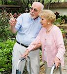 Senior couple taking a walk outdoors together.  She's using a walker.